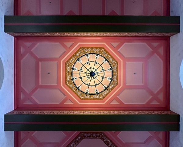 Eight sided chandelier on a painted ceiling with other octagons. 