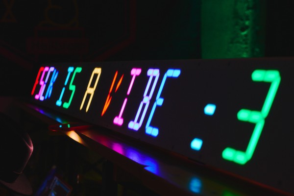 "FSCK is a vibe" on a colorful LED Segment display in a dimly lit room