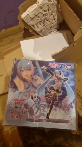 The box of hatsune miku x mlp figurine collab, a destroyed cardboard box visebl in the bacground