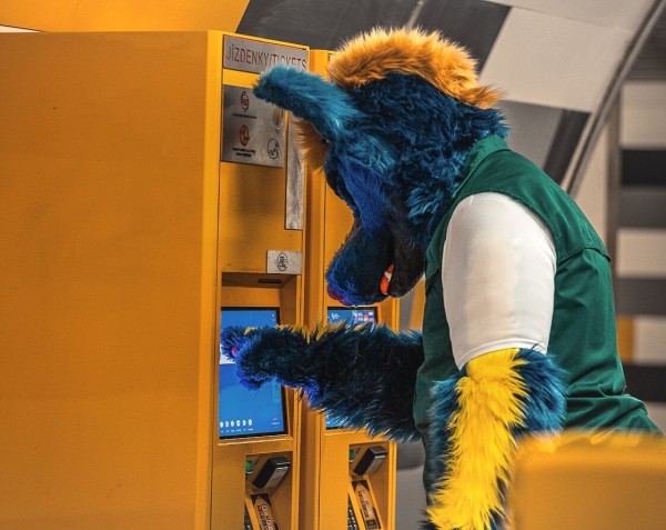 A picture of me in suit trying to operate a ticket machine. 
I'm depicted from the side pressing in the screen of a yellow ticket Machine, looking very confident. 