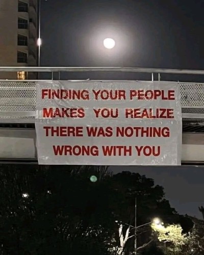 Sign hanging over a bridge that says “Finding your people makes you realize there was nothing wrong with you”