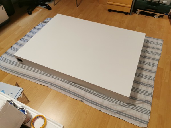 A large, flat white box laying on a blanket cover on the floor