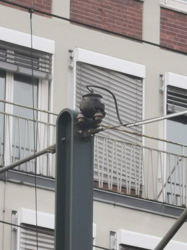 A pot-shaped thing on top of an overhead wire pole with a wire going into it