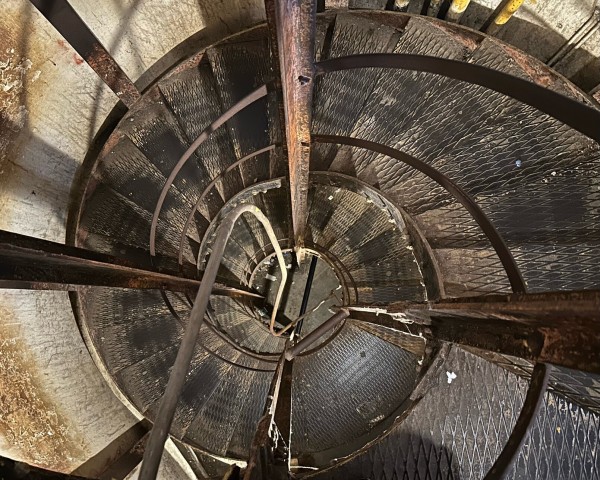 Direct downward view of a metal spiral stair case with many curving forms