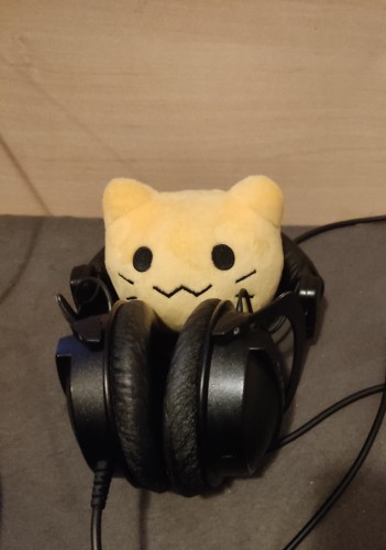 a blobcat plushie inside of my headphones which are laying on my bed. more accurately, the blobcat is between the headband and the ear cups of the headphones. the gap there is approximately blobcat sized.