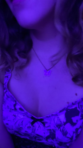 Ada under blue/black light wearing a bi-butterfly necklace and a ahegao bra