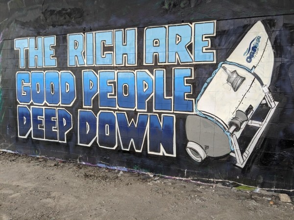 Painted on a wall: "The rich are good people deep down" with a drawing of the OceanGate Titan submarine pointed downwards